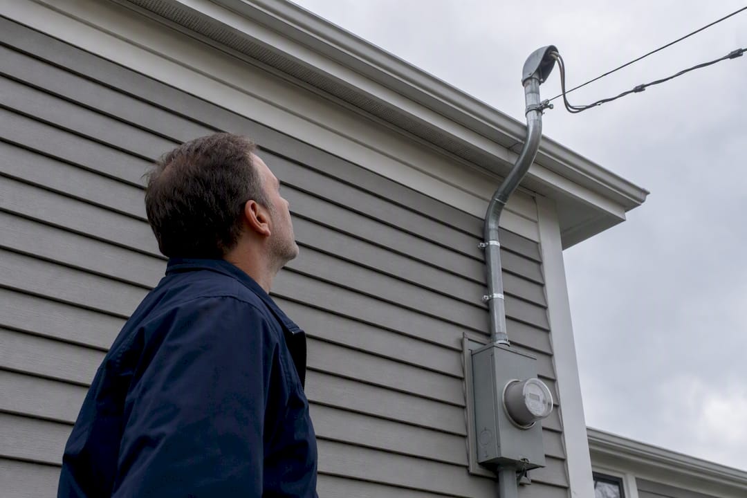 Homeowner examining exterior electrical service equipment