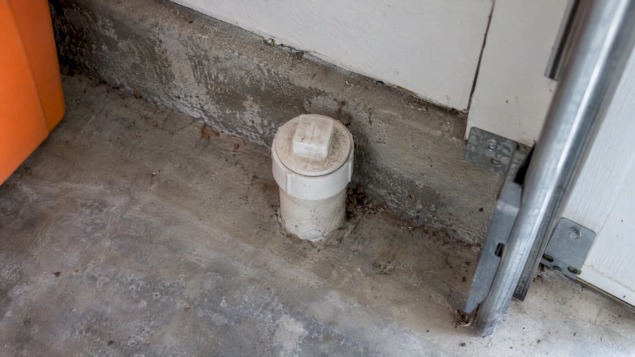 Capped sewer cleanout at garage wall